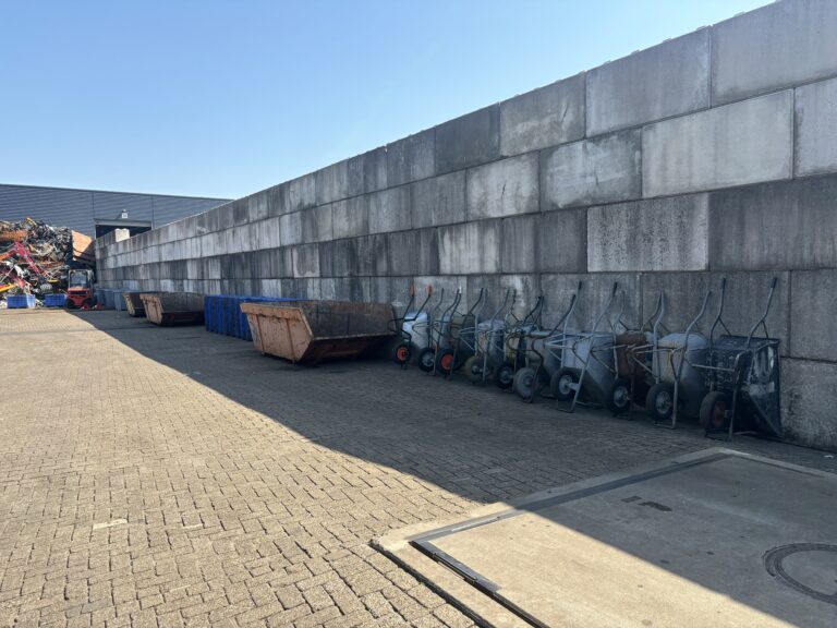 Containers en bakken langs de betonwand op het terrein