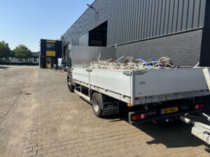 Vrachtwagen met laadbak vol oud ijzer bij de schroothandel
